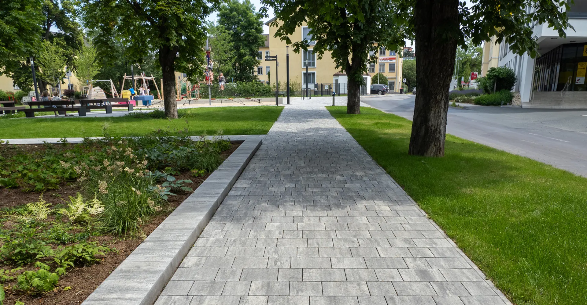 Sétány gyepfelületekkel és játszótérrel az oberwarti városi kertben; Magnum és Arret B25 VG4 térkő, gránitszürke árnyalt, Friedl Steinwerke.