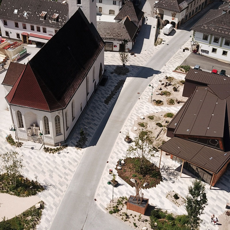 Begegnungszone Lunz am See Linea Rhomboid és Kursiva, taupe világos és sötét Légi felvétel a lunzi találkozózónáról Linea Rhomboid és Kursiva burkolattal, taupe világos és sötét színekben, templom körül, Friedl Steinwerke.