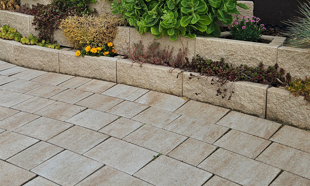 A Friedl Steinwerke Faro flórakosarak mészkő árnyalt színben egy lépcsőzetes támfalat alkotnak, előtte pedig Piazza térkő került lerakásra – így jött létre az egységes kombináció.