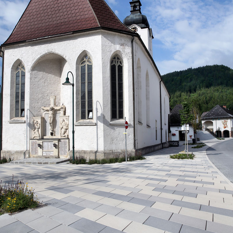 Begegnungszone Lunz am See Linea Rhomboid és Kursiva, taupe világos és sötét Templom előtti tér Lunz am See-ben Linea Rhomboid és Kursiva burkolattal, taupe világos és sötét színekben, Friedl Steinwerke.
