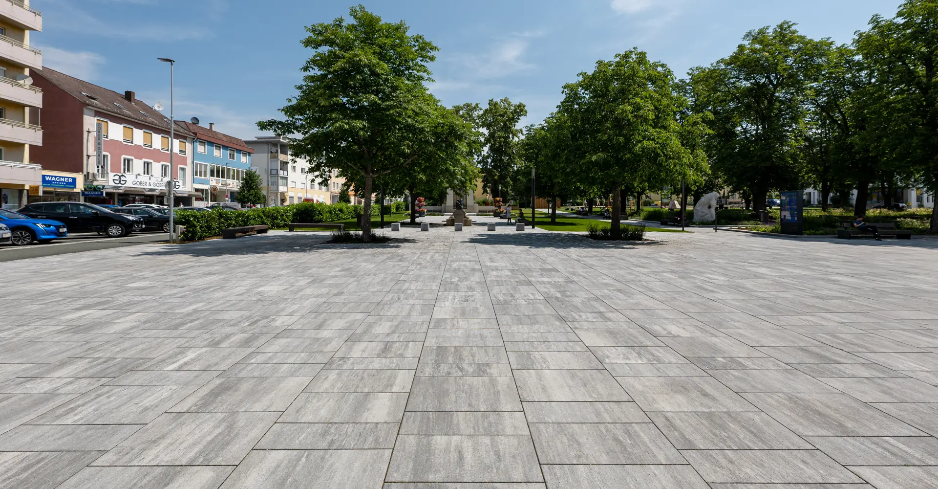 Tágas tér fákkal az oberwarti városi kertben; Magnum és Arret B25 VG4 térkő, gránitszürke árnyalt, Friedl Steinwerke.