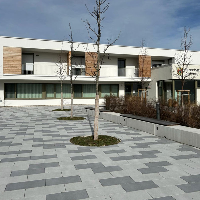 Gemeindezentrum Draßmarkt Linea VG4 térkő, platina világos és sötét árnyalt Draßmarkt központ előtti tér Linea VG4 térkővel, platina világos és sötét árnyalatban, letisztult vonalvezetés, Friedl Steinwerke.