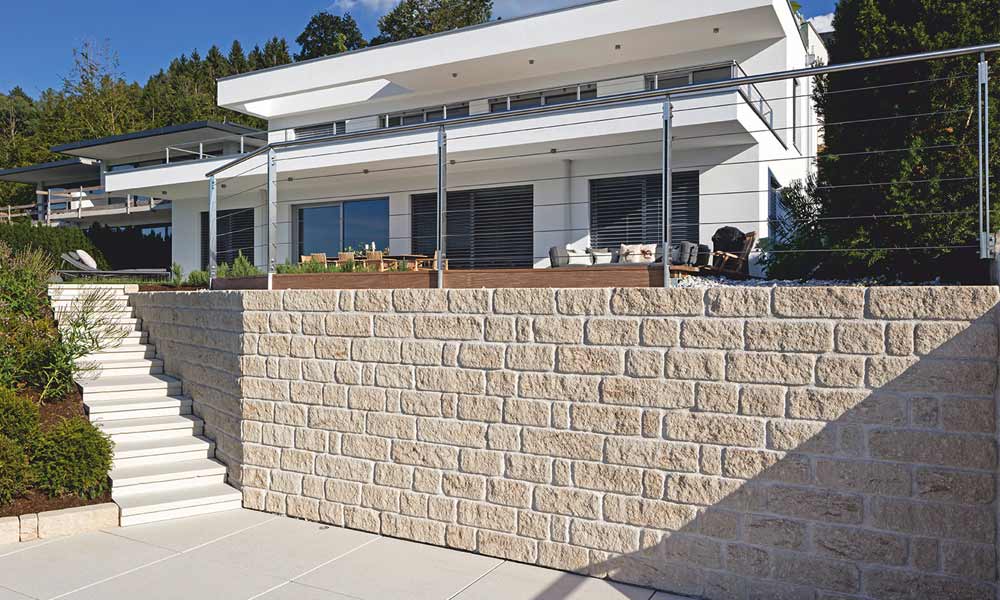 Gutshof falazókő MB16 koptatott, mészkő árnyalt habarcsfugával rakva a betonfal előtt, mint homlokzat Gutshof falazókő MB16 koptatott, mészkő árnyalt habarcsfugával rakva a betonfal előtt, mint homlokzat