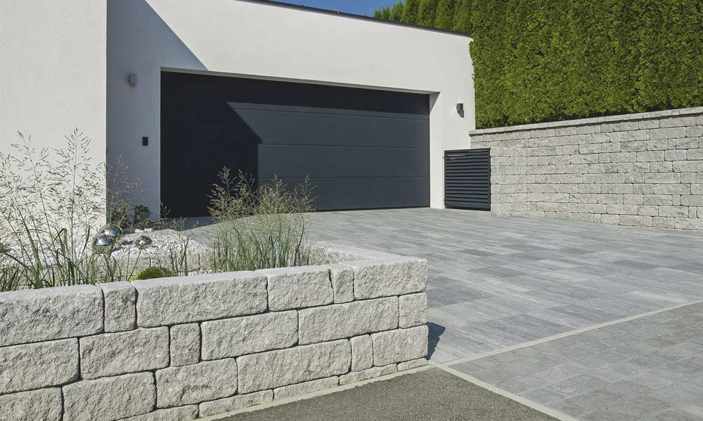 Gutshof falazókő MB16 koptatott, szürke határolóként 24 cm falszélességgel (MB24) és Gutshof fedlap 3 oldalon roppantott, szürke falként (háttérben) Gutshof falazókő MB16 koptatott, szürke határolóként 24 cm falszélességgel (MB24) és Gutshof fedlap 3 oldalon roppantott, szürke falként (háttérben)